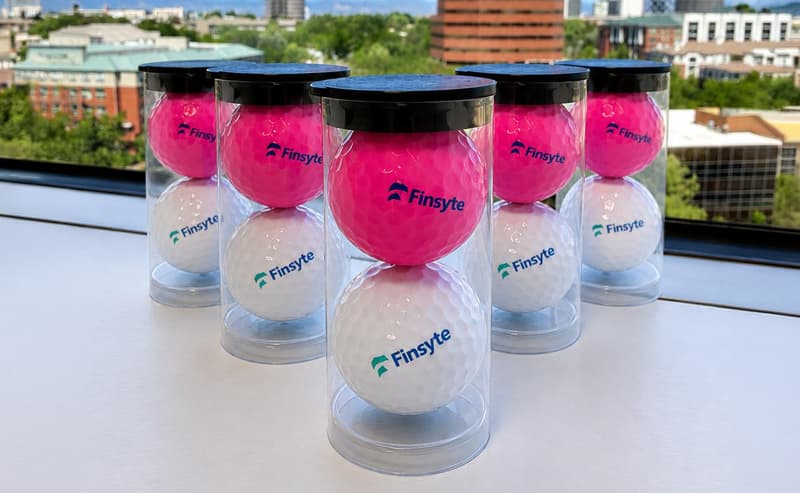 Pink and white Finsyte-branded golf balls in clear two-ball tubes